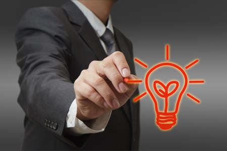 hand with a pen drawing light bulbの写真素材