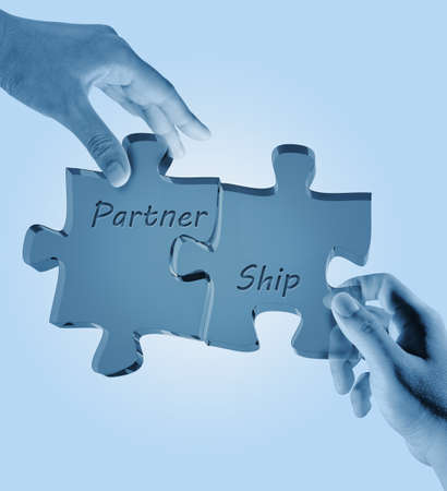 businessman and woman holding puzzle pieces with the word PARTNERSHIP written on it. 
