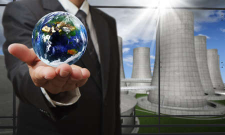 business man hand shows the earth and nuclear power plant background, elements of this image furnished by NASAの写真素材