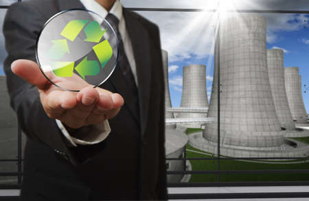 business man hand shows recycle sign and nuclear power plant backgroundの写真素材