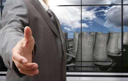 business man offers handshake with nuclear power plant backgroundの写真素材