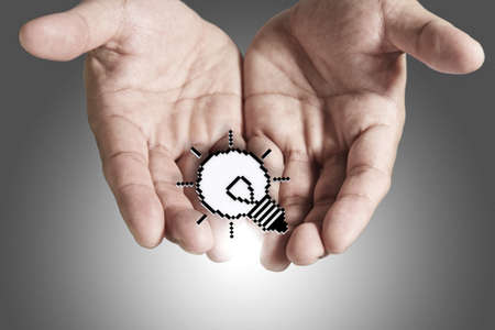 close up of open hand shows pixel light bulb sign as conceptの写真素材