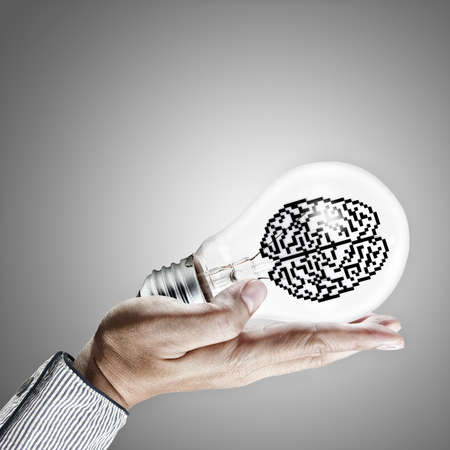 hand shows 3d pixel icon brain in light bulb as conceptの写真素材