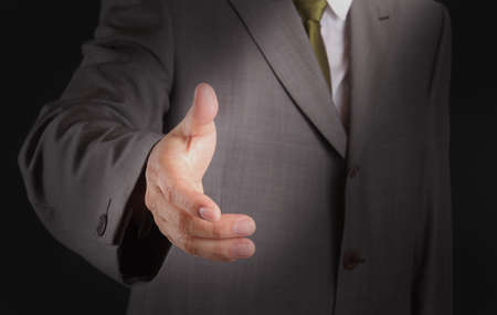 Businessman offering for handshake on dark backgroundの写真素材