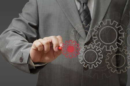 Man designing a mechanical system using old cog gear wheelsの写真素材