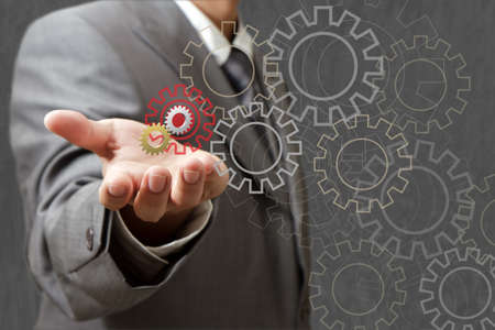 Man designing a mechanical system using old cog gear wheelsの写真素材
