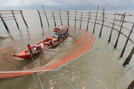 fishermen with yellow and orange sun in the backgroundの写真素材