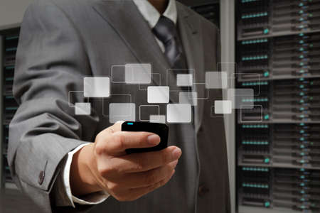 business man holds touch screen mobile phone in server roomの写真素材