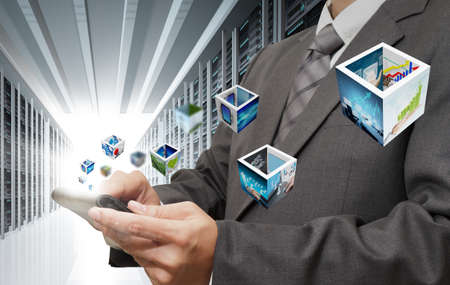 business man hand touch tablet computer streaming images in server roomの写真素材
