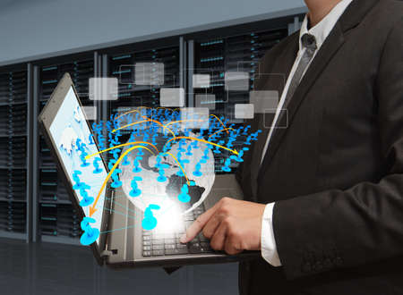 business man holds laptop computer and social network in server roomの写真素材