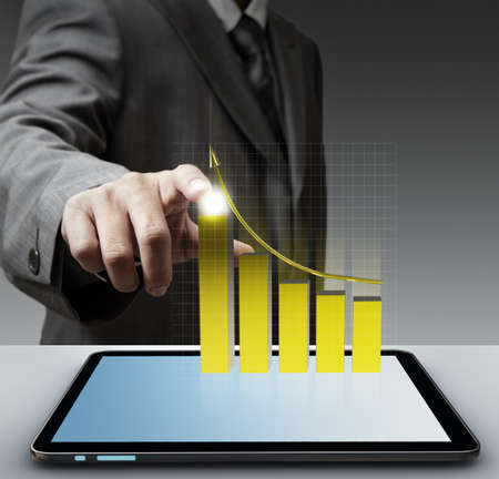 business man hand point to virtual gold graph with tablet computerの写真素材