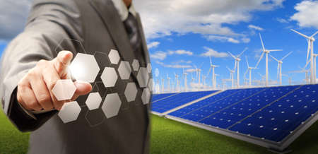 business man hand point virtual buttons and wind turbine and solar farm as conceptの写真素材