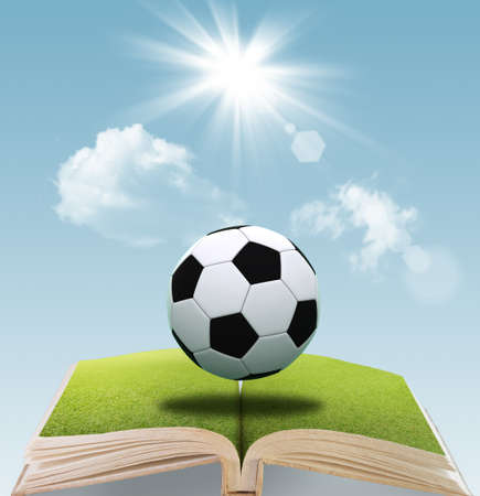 open book of soccer ball on green grass and blue sky backgroundの写真素材