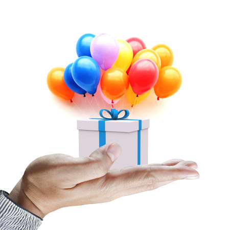 Hands holding gift in package with blue ribbon and colorful balloons isolated on whiteの写真素材