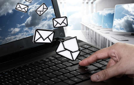 hand pushing laptop computer with pixel e-mail icon and sun and skyの写真素材