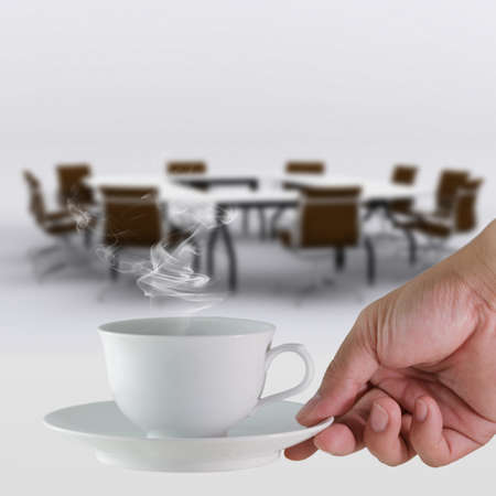 white coffee cup in hand business and meeting room backgroundの写真素材