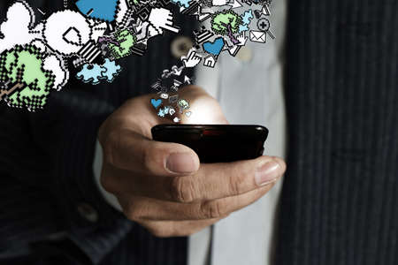 close up of touch screen mobile phone in businessman hand and pixel iconsの写真素材