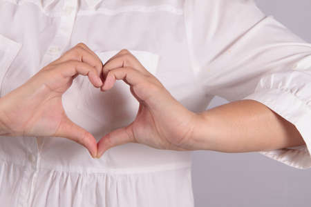 Shape of the heart made by female hands isolated on whiteの写真素材