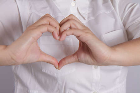 Shape of the heart made by female hands isolated on whiteの写真素材