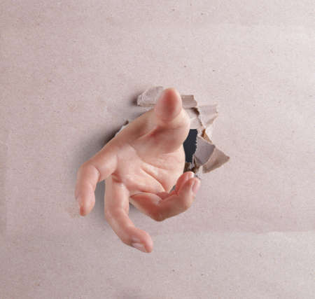 open hand breaking through textured backgroundの写真素材