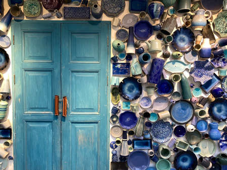 Vintage Traditional handcrafted plates on the wall background and wooden blue doors.の写真素材