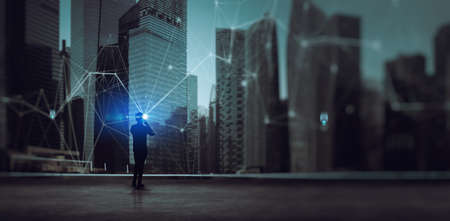 Businessman standing using smart phone in modern space watching modern city night view.Business Wireless network and Connection future technology concept.の写真素材