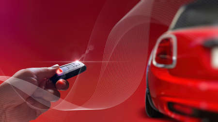 Men's hand presses on the smart remote control red car with technology transportation safety AR...