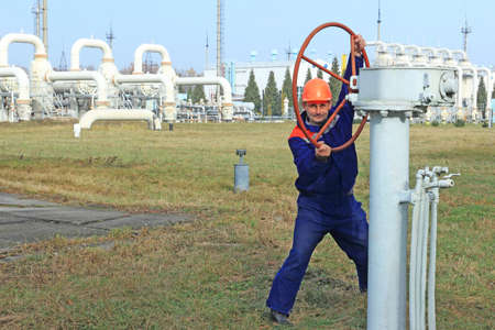 Worker opening big valve at gas compressor station, focus on manの写真素材