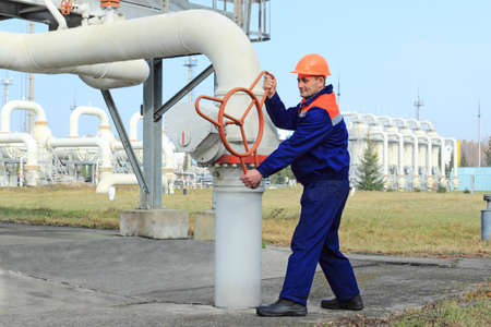 Worker turns valve on gas compressor station