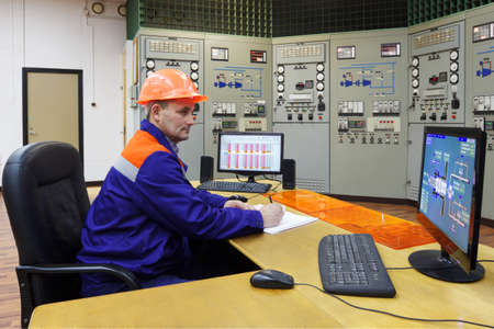 Engineer writes turbines parameters in log on main control panel of gas compressor stationの写真素材