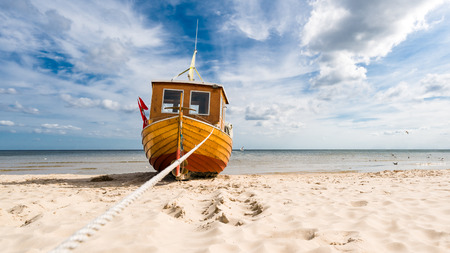 Small fishing boat on the Baltic Sea beach on the island of Usedom, on a beautiful sunny day.の写真素材