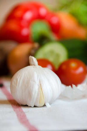 garlic and vegetables cucumber, carrots, potatoes, peppers, onions, basil, pepper on a white tableclothの写真素材