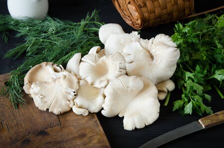 mushrooms black wooden table cutting board with herbsの写真素材