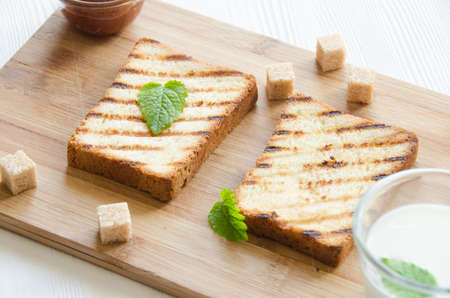 two toasts white bread cutting board with mint leavesの写真素材
