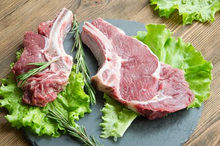 raw steak black plate wooden table with rosemary and herbs selective focusの写真素材