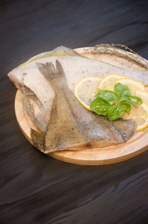 raw sole round board lemon basil on a black wooden backgroundの写真素材