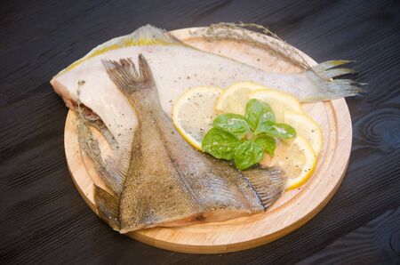 raw sole round cutting board lemon on a black wooden backgroundの写真素材