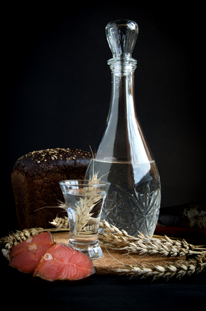 vodka glass decanter wheat bread salmon garlic on black background still lifeの写真素材