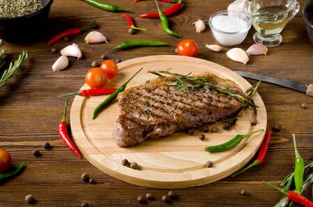rare steak wooden cutting board garlic spices on a brown wooden backgroundの写真素材