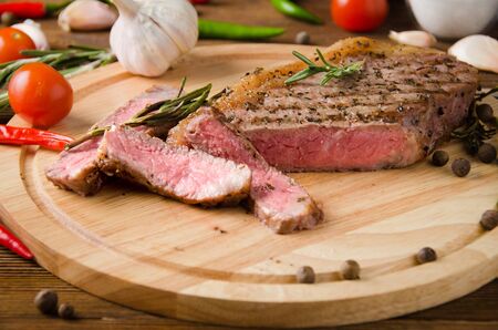 rare steak wooden cutting board spices on a brown wooden backgroundの写真素材