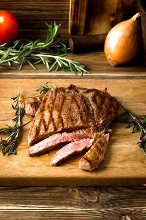 rare steak sliced wooden cutting board spices on a brown wooden backgroundの写真素材