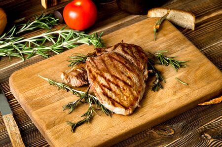 grilled steak rosemary rectangular wooden cutting board spices on a brown wooden backgroundの写真素材