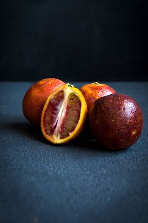 four red oranges on a dark textured backgroundの写真素材