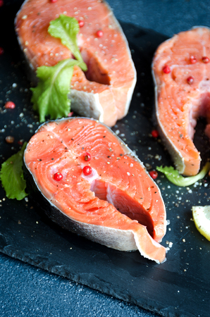 Salmon steaks pepper salt greens square plate lemon on dark background close-upの写真素材