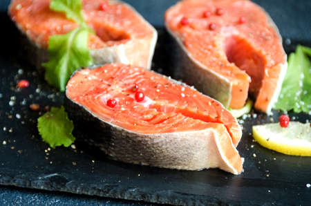 Salmon steaks pepper greens black square plate lemon on dark background close-upの写真素材
