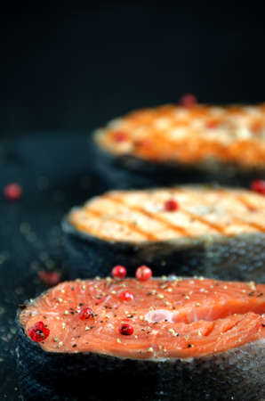 group salmon steaks pepper salt black plate on dark background close-upの写真素材