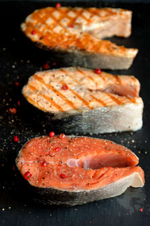 Sallmon steaks pepper dark square plate on dark background close-upの写真素材