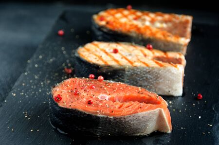 several salmon steaks pepper dark square plate on dark background close-upの写真素材