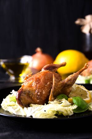 quail fowl baked salad leaves basil spices on a black plate close upの写真素材