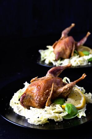 pair quail fowl baked salad leaves basil on a black plate close upの写真素材